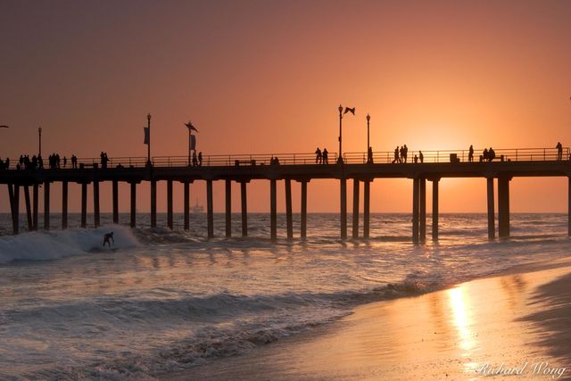 Surfer Riding Wave at Sunset Next to Huntington Beach Pier, California, photo