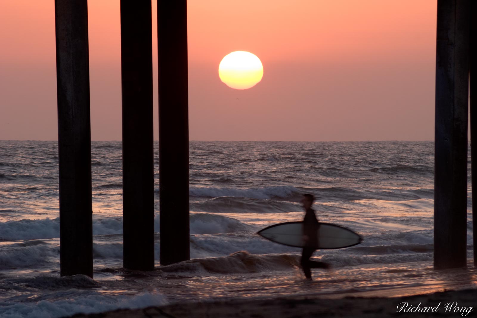 Surfer Running into Surf at Sunset Under Huntington Beach Pier, California, photo